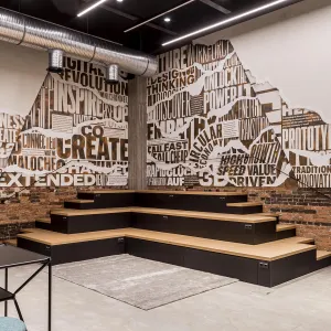 Paneled seating area with wall graphics in newspaper look that can be seen under the seemingly torn off layers of wallpaper, words are visible in different fonts