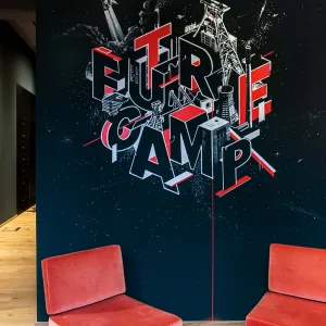 Accenture Future Camp Wandgrafik in Weiß und Rot auf einer schwarzen Wand, die Buchstaben aus dem Wort Future Camp wurden in die Illustration miteingearbeitet