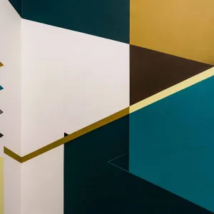 Geometric shapes and lines run across several walls in shades of blue and mustard yellow