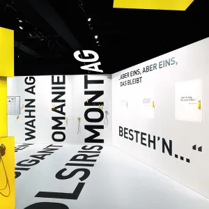 Raumteil mit großen schwarzen Lettern, die vom Boden, über die Wand, bis an die Decke laufen und bekannte Vereins-Zitate zeigen