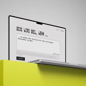 Ein Laptop auf einem leuchtend gelben Podest zeigt eine Website mit dem Titel 