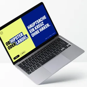 Laptop Screen der Demo-Mat Webseite, mit der zufällig zusammengestellten Botschaft: Ob Hipster oder Landei, Hauptsache ein Kreuz ohne Haken