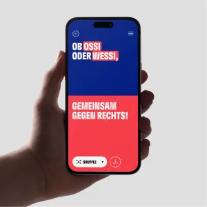 Smartphone screen colored half in dark blue and half in red, the message stands out in white text: Whether Ossi or Wessi, together against the right! With the shuffle button at the bottom left of the screen, new messages can be compiled with a single click.