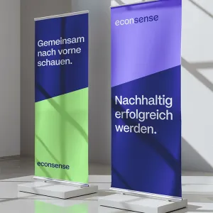 Two roll-up banners in econsense branding in blue and green tones, featuring the claims “Looking ahead together.” and “Achieving sustainable success.”