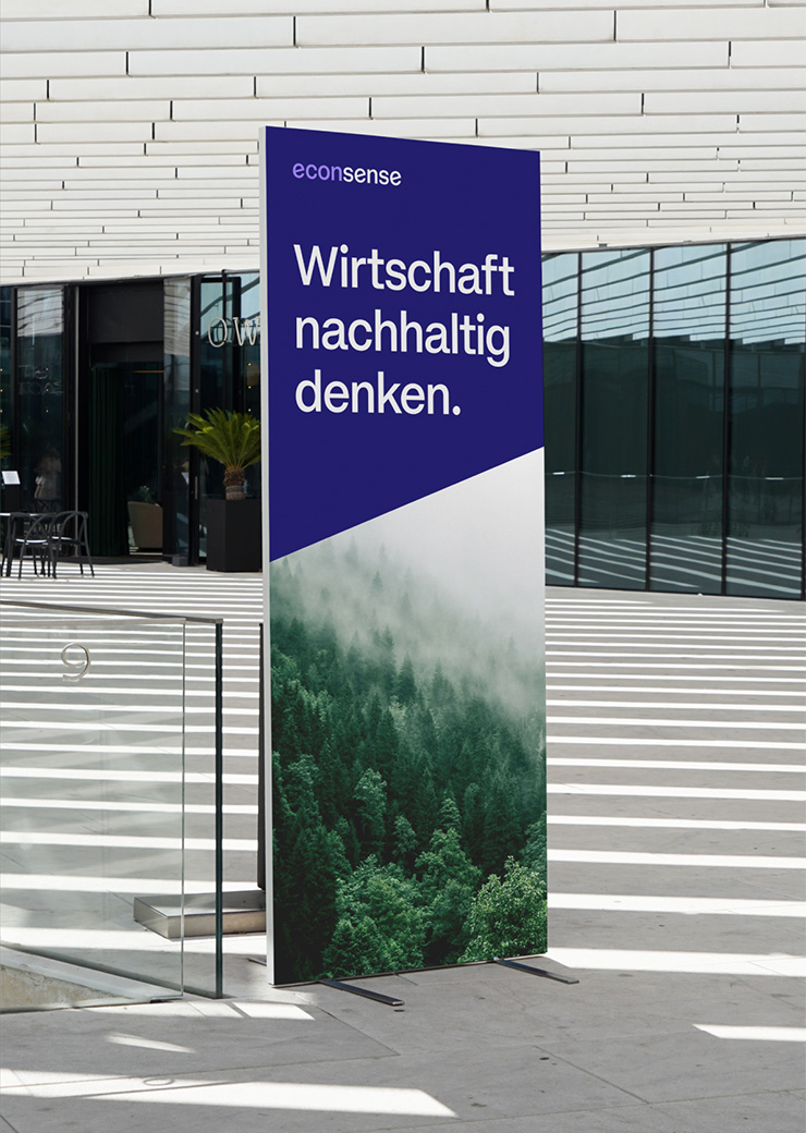 Freistehendes Display im econsense Design in Blau- und Grüntönen mit Naturmotiv und dem Claim „Wirtschaft nachhaltig denken.“