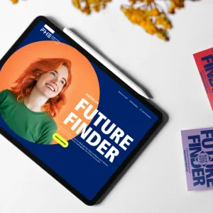 Auf einem Tisch liegen ein Tablet, auf dem die Startseite des Future Finders zu sehen ist. Daneben liegen zwei Stapel mit Stickern in rot und lila, die auf den Future Finder aufmerksam machen.