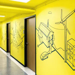 The corridor wall opposite the large letters shows elements for renewable energy generation in a reduced line style