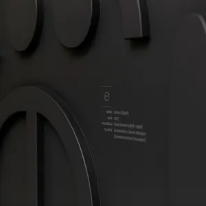 Detail of black haptic letters attached to the black corridor wall, a text block adhered next to it explains to the viewer which font it is and who designed it