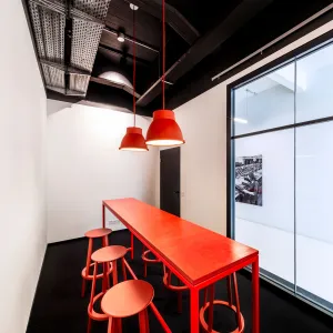 White walls, a glass front, black ceiling and floor make up the meeting room, which is filled with red furniture