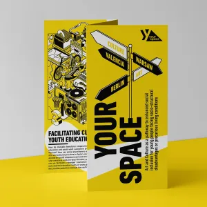 Faltflyer des europäischen Projekts „Your Space“ zur Förderung kultureller Jugendbildung in Berlin, Warschau und Valencia steht aufgefaltet auf einer gelben Oberfläche vor grauem Hintergrund. Der Flyer zeigt Illustrationen urbaner Räume sowie Themen wie Capacity Building und partizipative Jugendkultur, passend zum Ziel des Projekts, benachteiligte Jugendliche durch Kunst und kulturelle Aktionen zu stärken und gesellschaftliche Teilhabe zu fördern