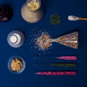 Test tubes, measuring beakers and Erlenmeyer flasks filled with different types of colorful sprinkles